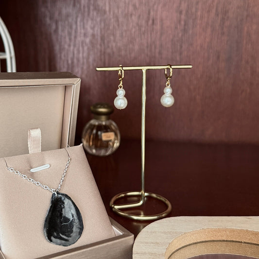 Jewelry set including necklace and earrings displayed on a table with a lamp in the background.