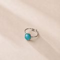 Silver ring with a turquoise gemstone on a beige background
