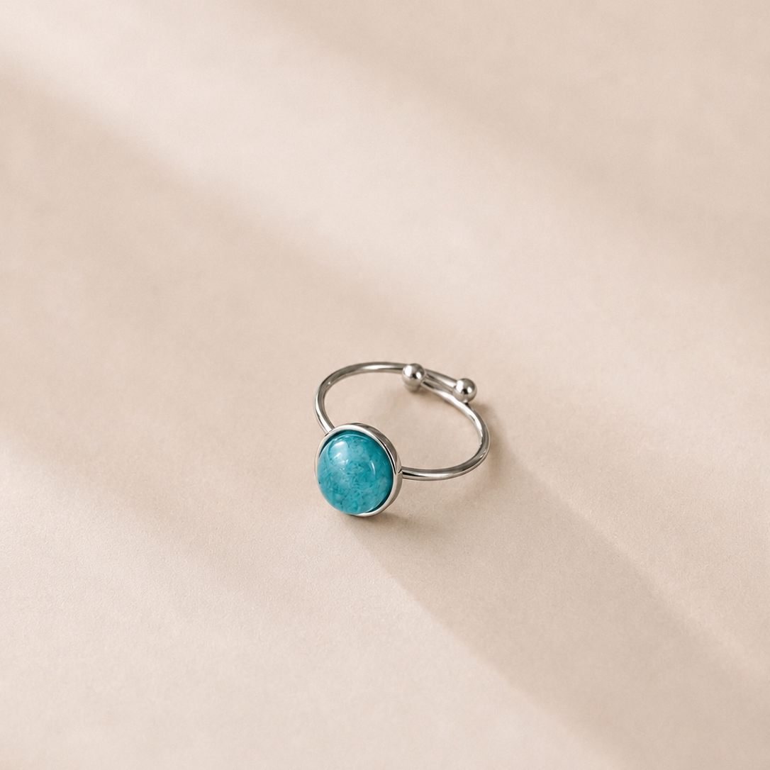 Silver ring with a turquoise gemstone on a beige background