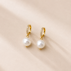 Gold hoop earrings with pearl drops on a beige background