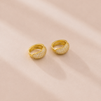 Gold hoop earrings on a soft pink background