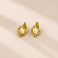 Pair of gold earrings with pearl centers on a beige background