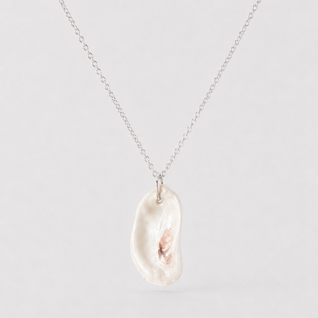 Necklace with a large, irregularly shaped pearl pendant on a light gray background