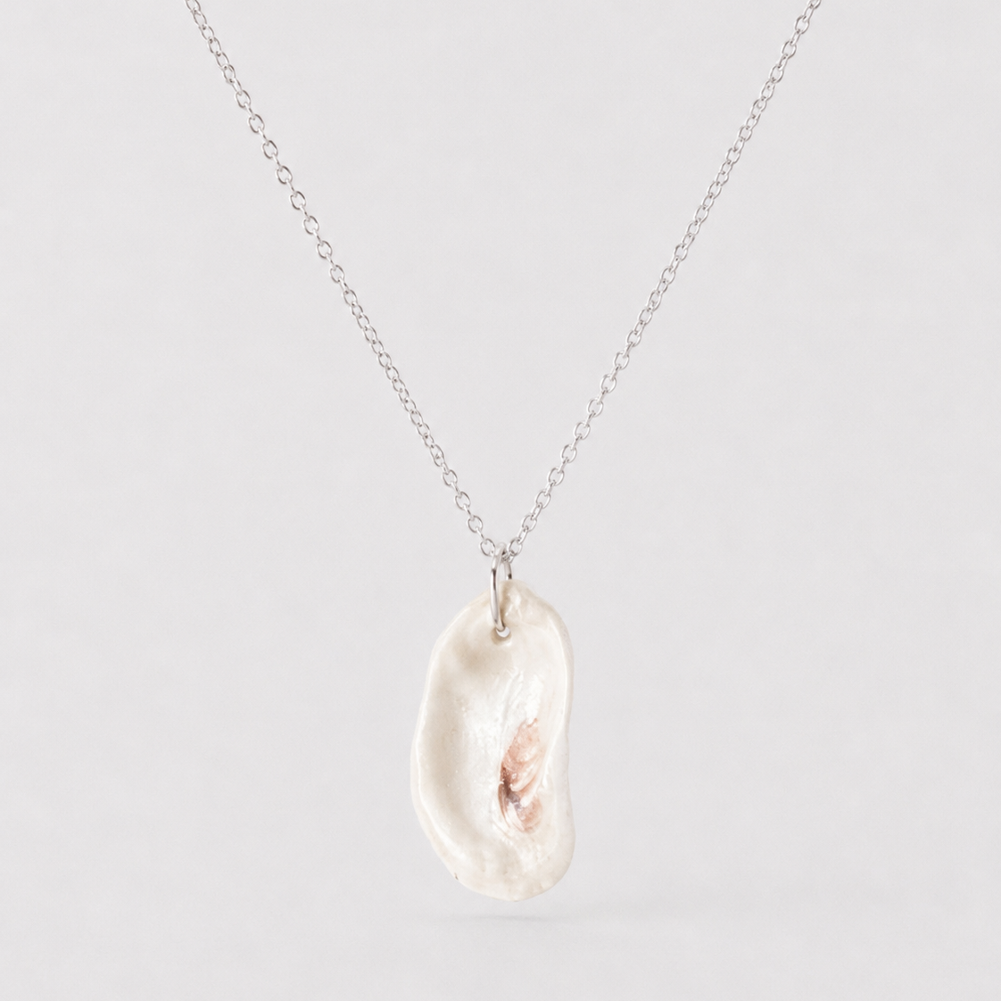 Necklace with a large, irregularly shaped pearl pendant on a light gray background