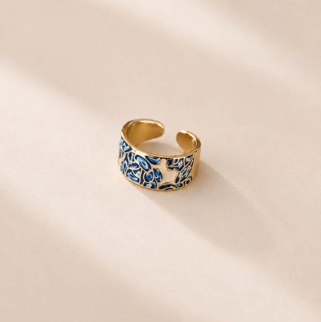 Gold ring with blue and white pattern on a beige background