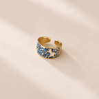 Gold ring with blue and white pattern on a beige background