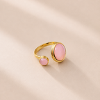 Gold ring with pink stones on a beige background