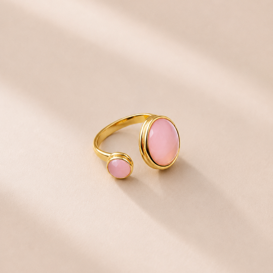 Gold ring with pink stones on a beige background
