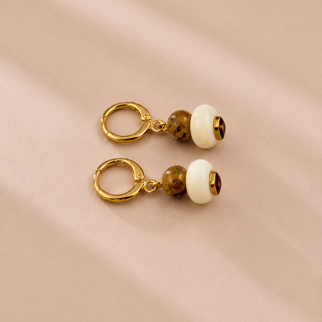 Pair of earrings with gold rings and round beads on a beige background