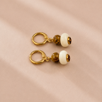 Pair of earrings with gold rings and round beads on a beige background