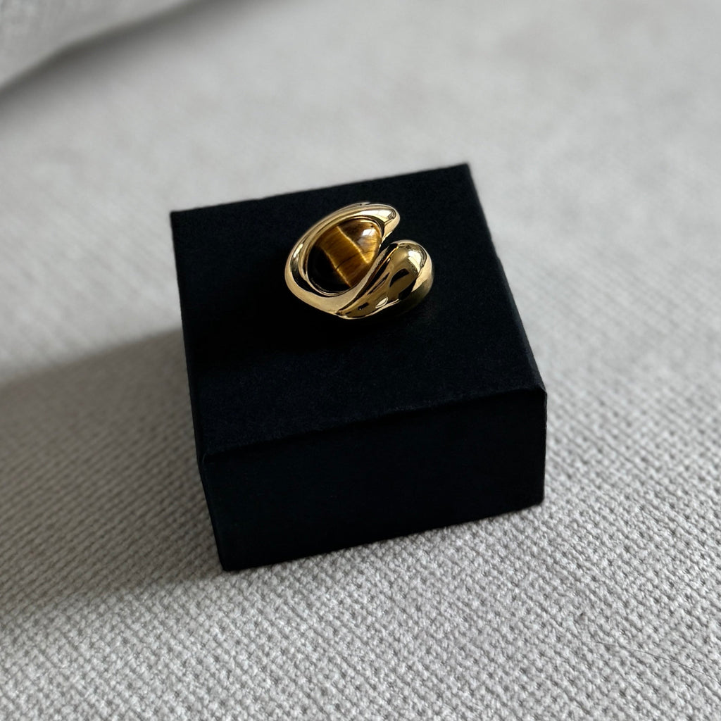 Gold ring on a black box against a light gray background