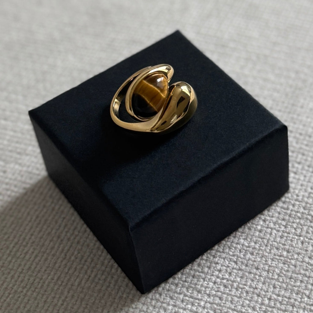 Gold ring on a black box against a gray background