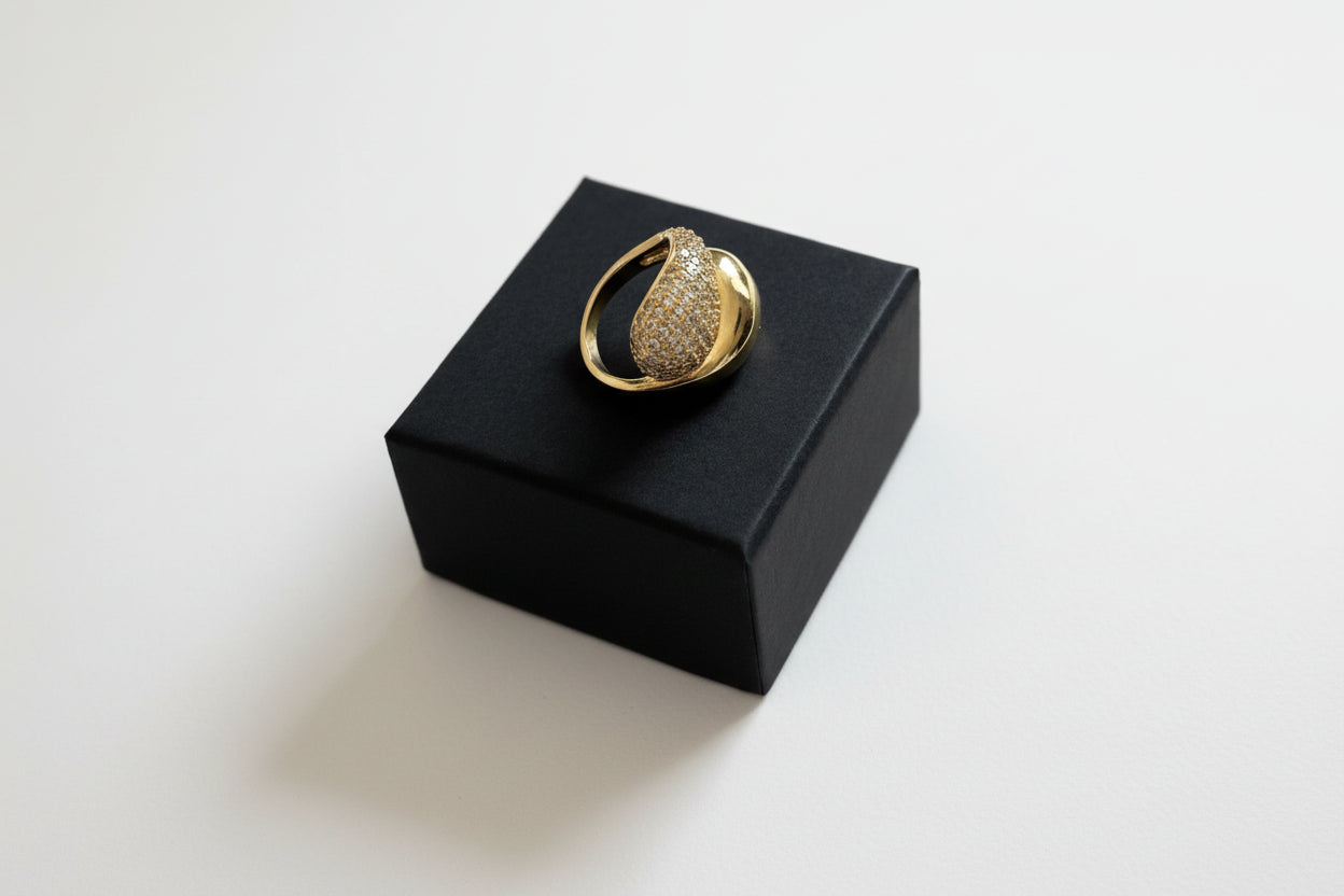 Gold ring with diamonds on a black box against a gray background