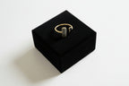 Gold ring on a black jewelry box with a light gray background