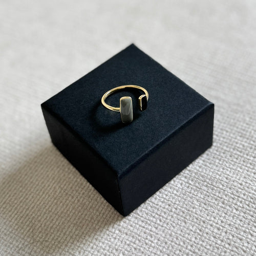 Gold ring on a black jewelry box with a light gray background