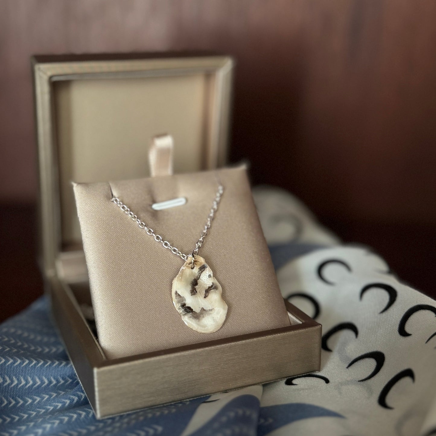 Necklace with a pendant in an open jewelry box on a textured surface