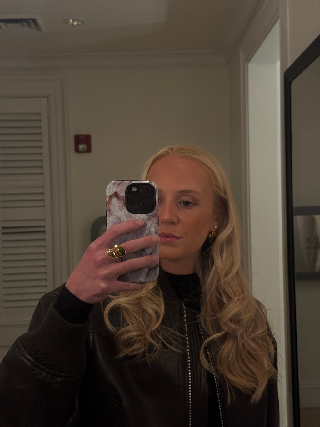 Person taking a mirror selfie wearing a black leather jacket.