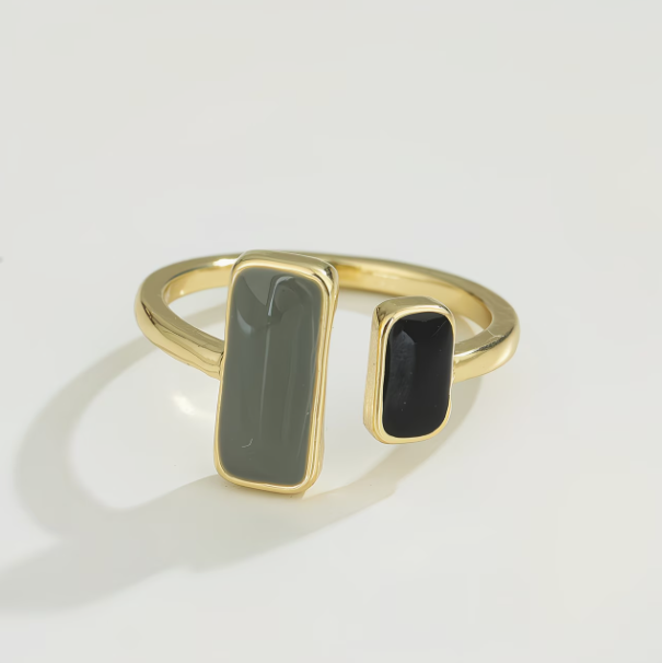 Gold ring with two rectangular gemstones on a light gray background