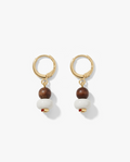 A pair of gold hoop drop earrings featuring a small dark brown wooden bead, a larger white spherical bead, and a tiny red accent bead at the bottom, displayed on a clean white background.
