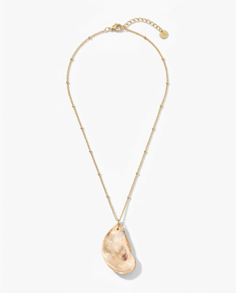A gold chain necklace featuring a large, organic-shaped peach-colored stone pendant, displayed on a clean white background.