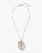 A silver chain necklace featuring a large, organic-shaped polished oyster shell pendant in a champagne or light beige tone, displayed against a clean white background.