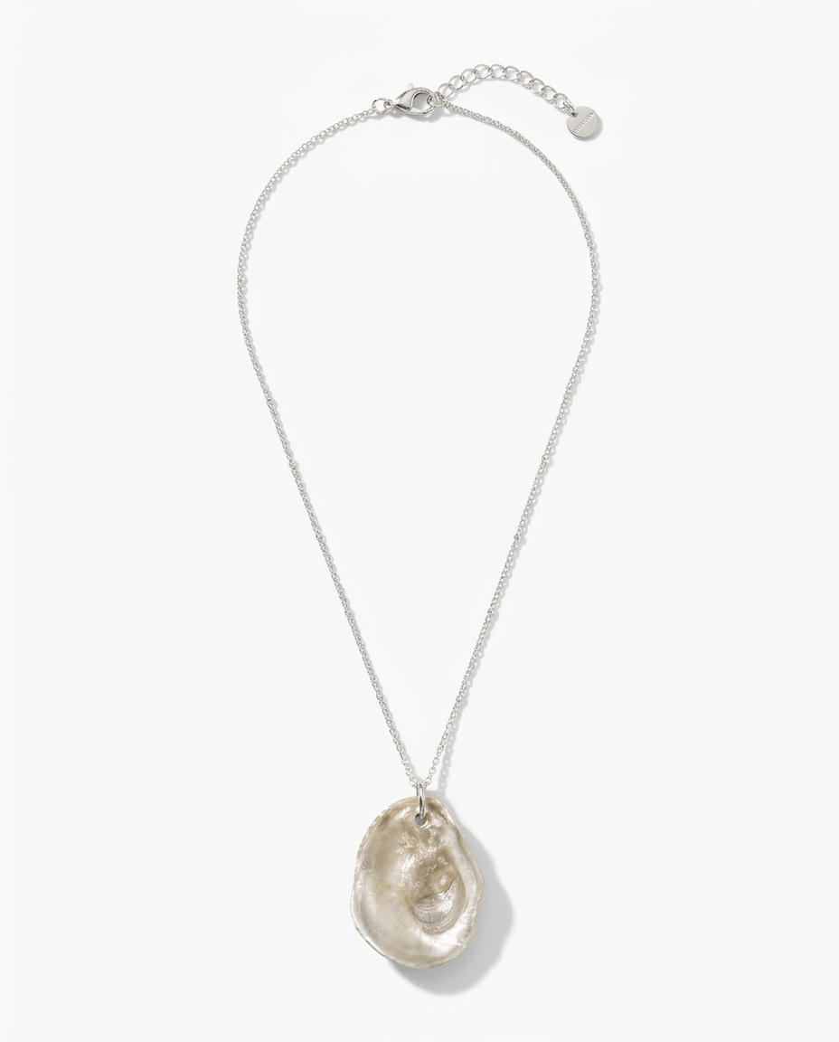 A silver chain necklace featuring a large, organic-shaped polished oyster shell pendant in a champagne or light beige tone, displayed against a clean white background.