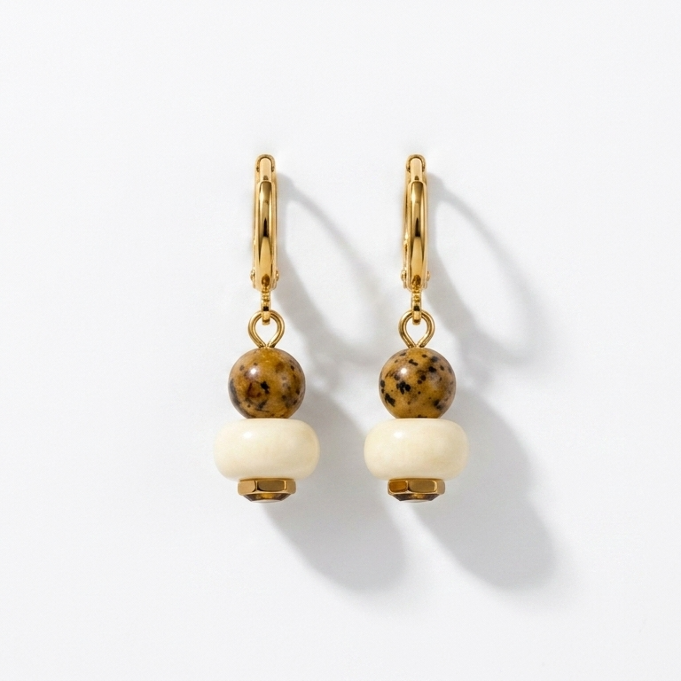 Pair of gold earrings with white beads on a light gray background