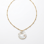 Necklace with a round, white pendant on a gold chain against a white background