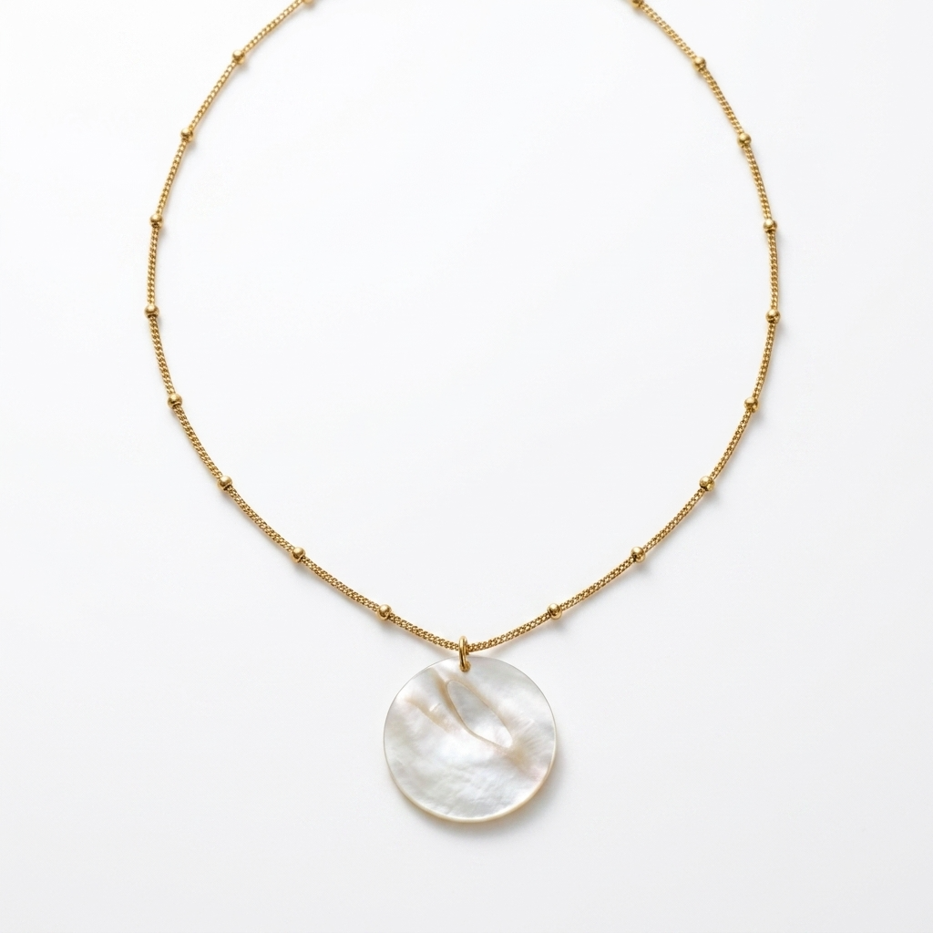 Necklace with a round, white pendant on a gold chain against a white background